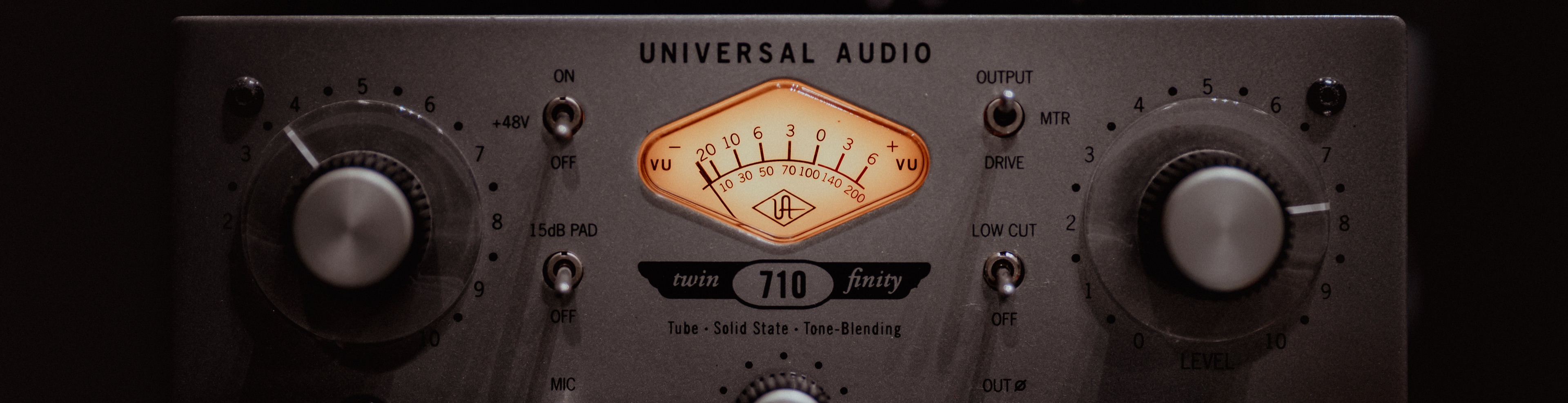 Close-up of a Universal Audio 710 Twin-Finity preamp with a glowing VU meter